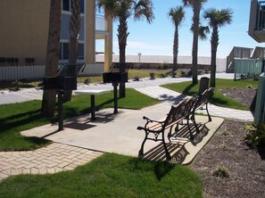A courtyard with benches, a mailbox, and a palm tree. - Pelican Isle 406 - Sunset Shores (Fort Walton Beach)