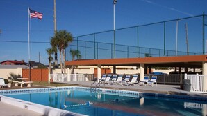A swimming pool with lounge chairs, a flag, and a fenced area. - Surf Dweller 402 - Seashell Haven (Fort Walton Beach)