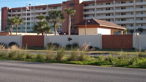 A multi-story hotel with a flat roof, palm trees, and a clear sky. - Surf Dweller 402 - Seashell Haven (Fort Walton Beach)