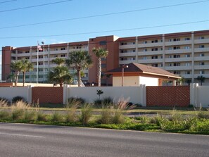 A multi-story hotel with a flat roof, palm trees, and a clear sky. - Surf Dweller 402 - Seashell Haven (Fort Walton Beach)