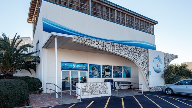 Ein Gebäude mit einer Steinfassade, einem blauen Wellendesign und einem Schild für den 'Gulfarium Marine Adventure Park'.