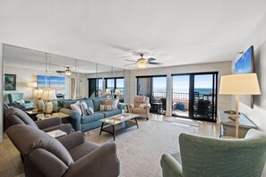 A spacious living room with a large sofa, armchairs, a coffee table, and a balcony with a view of the ocean. - Surf Dweller 205 - Seaspray Getaway (Fort Walton Beach)