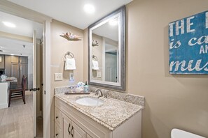 Une salle de bain avec un grand miroir, un lavabo et un porte-serviettes.