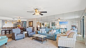 Ein geräumiges Wohnzimmer mit einer großen Couch, Sesseln, einem Couchtisch und einem Essbereich im Hintergrund.