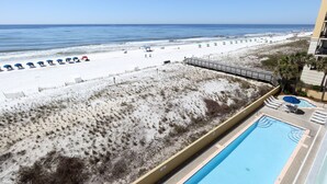 Vista de una playa con piscina, sombrillas y sillas de descanso.