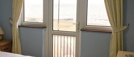 A hotel room with a bed, a nightstand, a dresser, and a window with curtains.