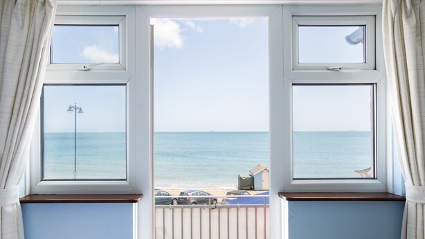 A view through a window with a view of the sea and beach.