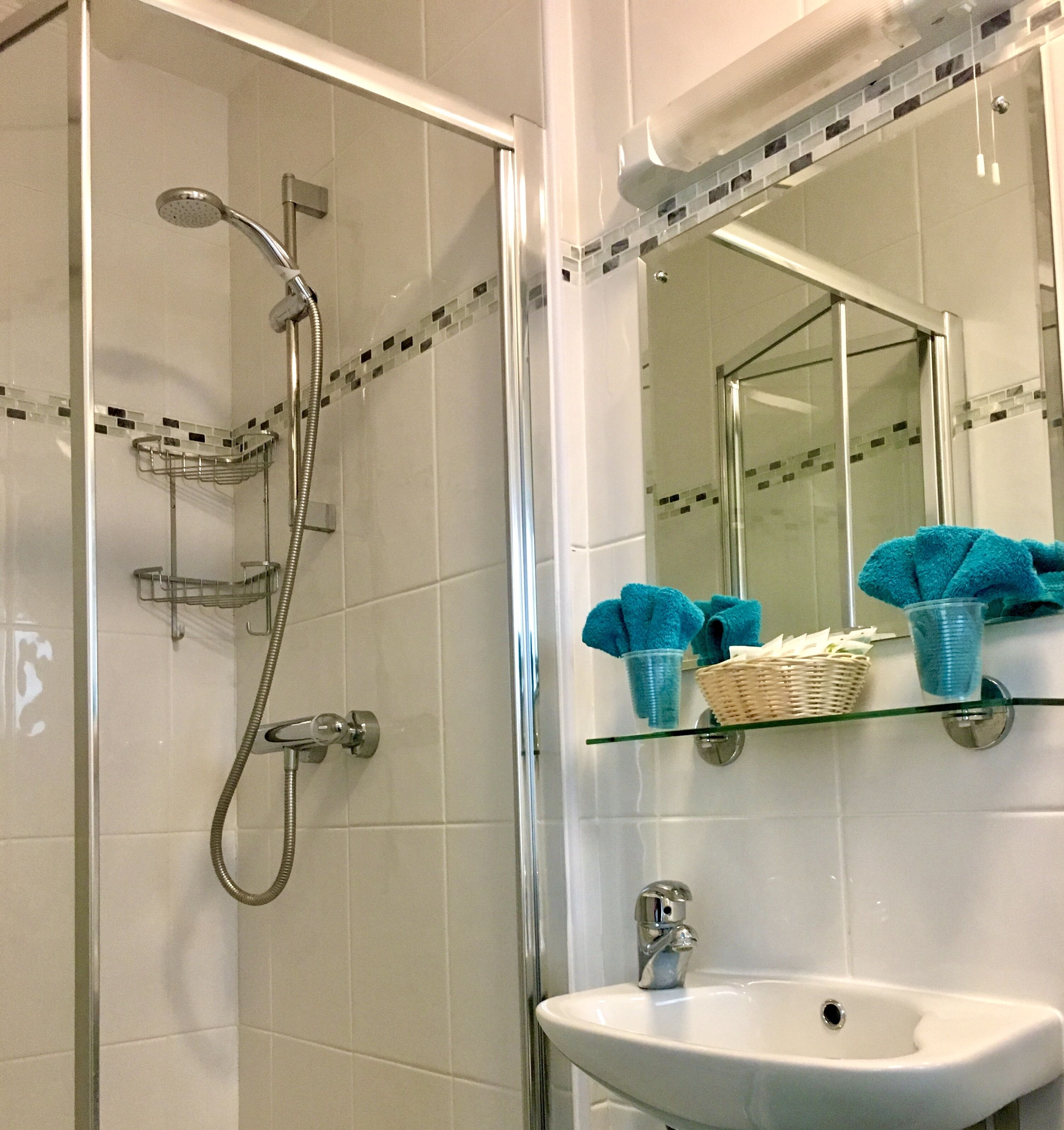 A bathroom with a glass shower enclosure, a white sink, and a mirror above the sink.