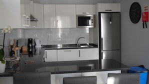 A modern kitchen with white cabinets, stainless steel appliances, a microwave, and a refrigerator.