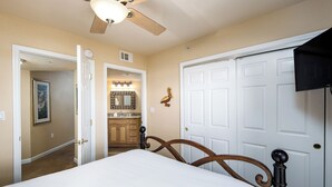 A bedroom with a bed, a ceiling fan, and a white door. - Islander 5003 - Breezy Beachside (Fort Walton Beach)