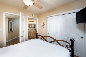 A bedroom with a bed, a ceiling fan, and a white door. - Islander 5003 - Breezy Beachside (Fort Walton Beach)