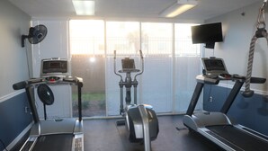 Een fitnessruimte met loopbanden, een crosstrainer en een hometrainer.