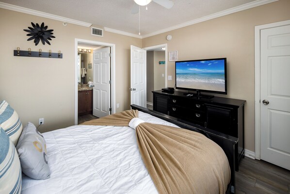 A bedroom with a bed, a television, a dresser, and a door. - Island Princess 610 - Sunshine Sands (Fort Walton Beach)