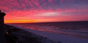 Een strand met een zonsondergang en een gebouw op de voorgrond.