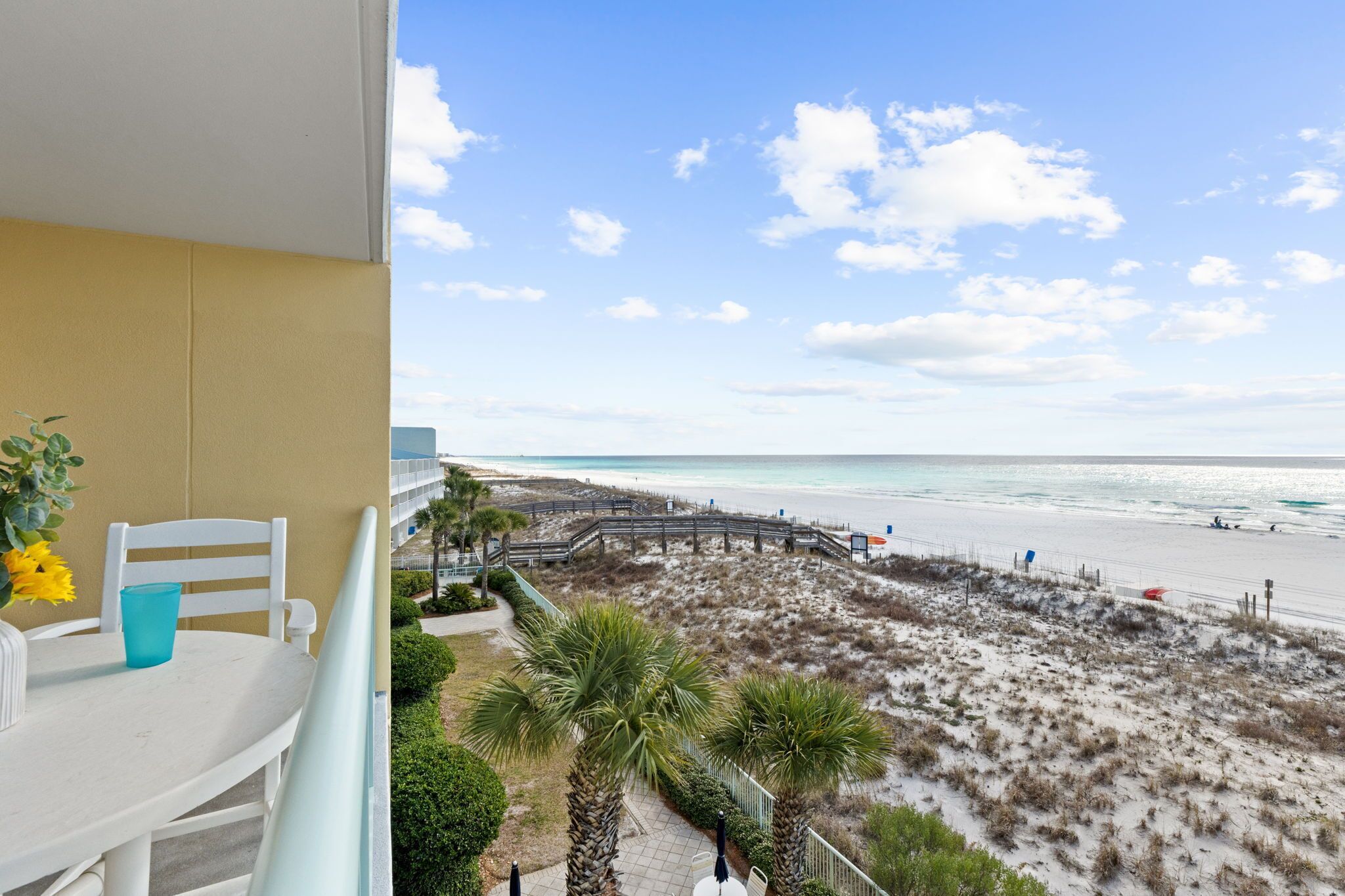 Un balcone con vista sulla spiaggia e una passerella in legno.