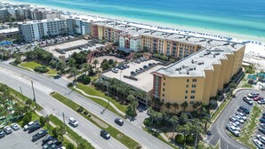 Une vue aérienne d’un hôtel à plusieurs étages, avec un parking et une vue sur la plage.