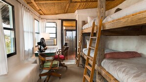 A rustic room with bunk beds, a desk with a chair, and a ladder. - Mimi's Bunkroom - just outside of Big Bend Nt'l Park (Terlingua)