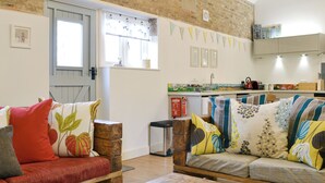 A cozy living room with a wooden sofa, a coffee table, and a kitchen in the background. - 4 bedroom accommodation in Driffield, near Bridlington (Driffield, near Bridlington)