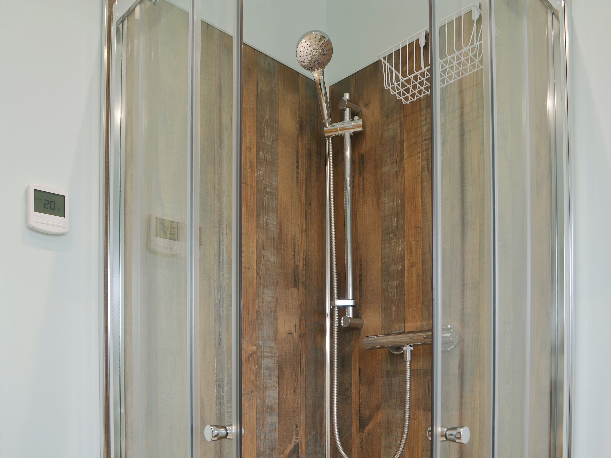 A shower enclosure with a wooden panel design, a handheld showerhead, and a wall-mounted control panel.