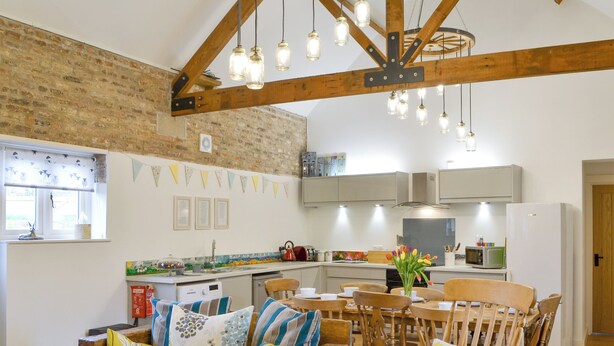 A cozy kitchen with wooden beams, a dining area with a wooden table and chairs, and a sofa with patterned cushions. - 4 bedroom accommodation in Driffield, near Bridlington (Driffield, near Bridlington)