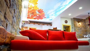 A modern living room with a stone wall, a red sofa, and a ceiling mural. - Apartament "Pomigranaj"  for 4 person (Marezige)
