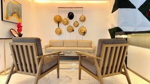 A modern living room with a sofa and two armchairs, a wall-mounted hat rack, and a geometric wall decoration. - Hotel Puerto Pacifico Guayaquil Airport (Guayaquil)