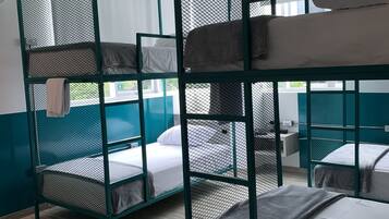 Habitación tipo dormitorio con literas, suelo de madera y ventana con vistas a zonas verdes.
