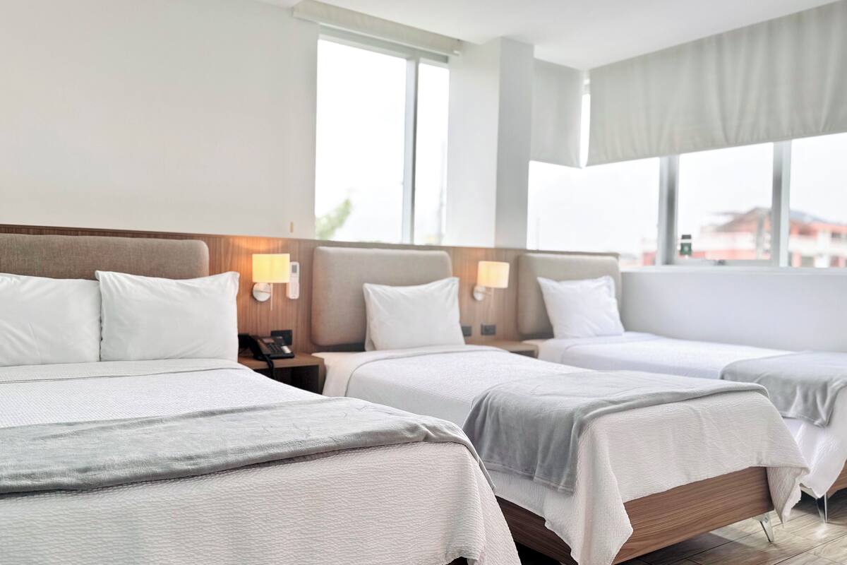 Habitació d'hotel amb dos llits, cadascun amb capçalera, taules de nit i làmpades.