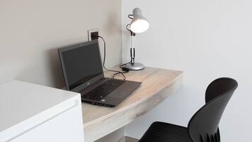 A modern office desk with a laptop, a desk lamp, and a black office chair.