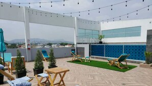 A rooftop terrace with wooden lounge chairs, a small table, and potted plants. - Hotel Puerto Pacifico Guayaquil Airport (Guayaquil)