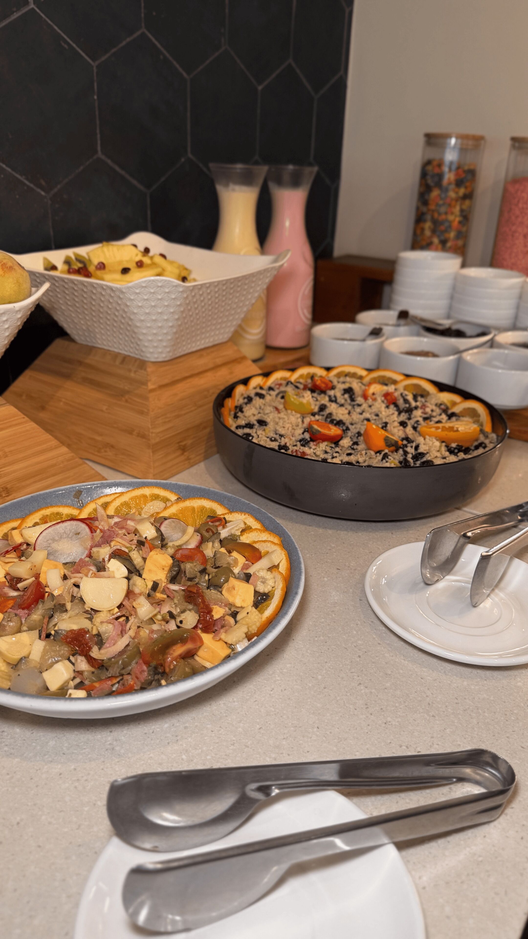 Una mesa de buffet con diversos platos, incluyendo un cuenco de frutas, una ensalada y un plato de cazuela.