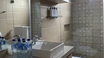 A modern bathroom with a large sink, a mirror, and a shower area.