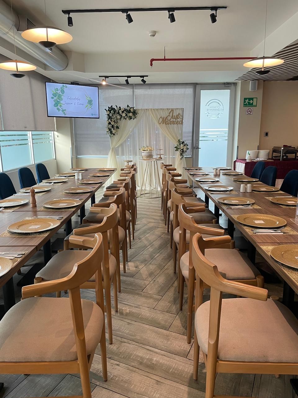 Uma sala de conferências com mesas compridas, cadeiras e palco com decorações florais.