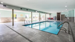 Una amplia piscina interior con agua cristalina, rodeada de suelos y paredes de azulejos.