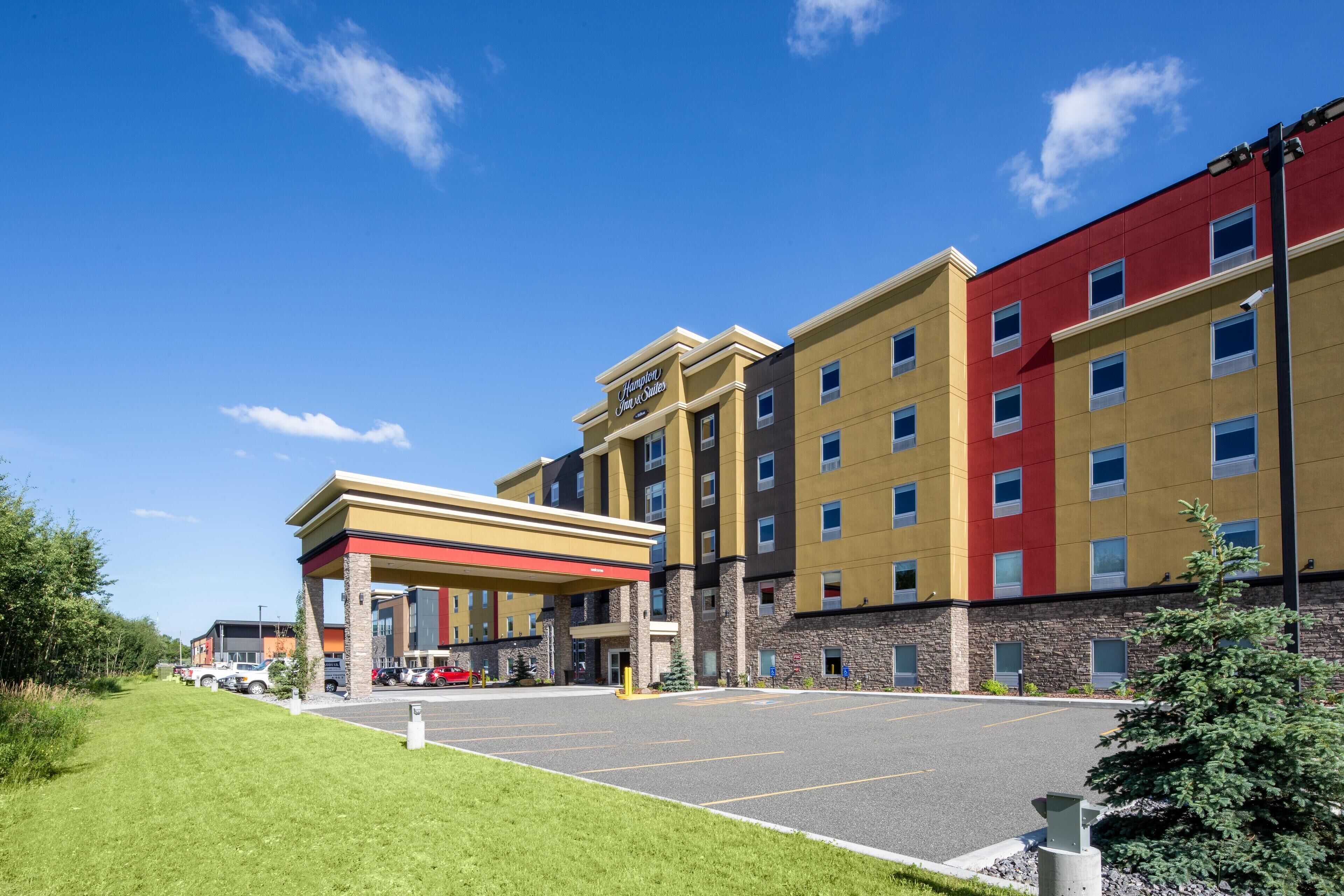 Un hôtel à plusieurs étages comprenant une station-service, un parking et une pelouse bien entretenue.