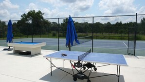 Ein Tennisplatz im Freien mit zwei Tischtennisplatten und einem Billardtisch.