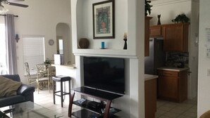 Ein Wohnzimmer mit Fernseher, einer Couch, einem Couchtisch und einem Essbereich mit Stühlen und Tisch.