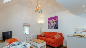 Een moderne woonkamer met een bank, een eettafel en een schilderij aan de muur.