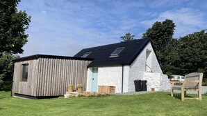 Een modern huis met een houten uitbouw, een gevel van natuursteen en een schuin dak.