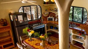 Uma cozinha com ilha revestida de azulejos, cadeiras de madeira, geladeira e fogão.