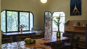 Uma sala de jantar com uma mesa de mosaico, cadeiras de vime, um fogão a gás e vasos decorativos.