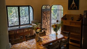 Cozinha com piso de azulejos, mobiliário de madeira, fogão e janela com detalhe em ferro.