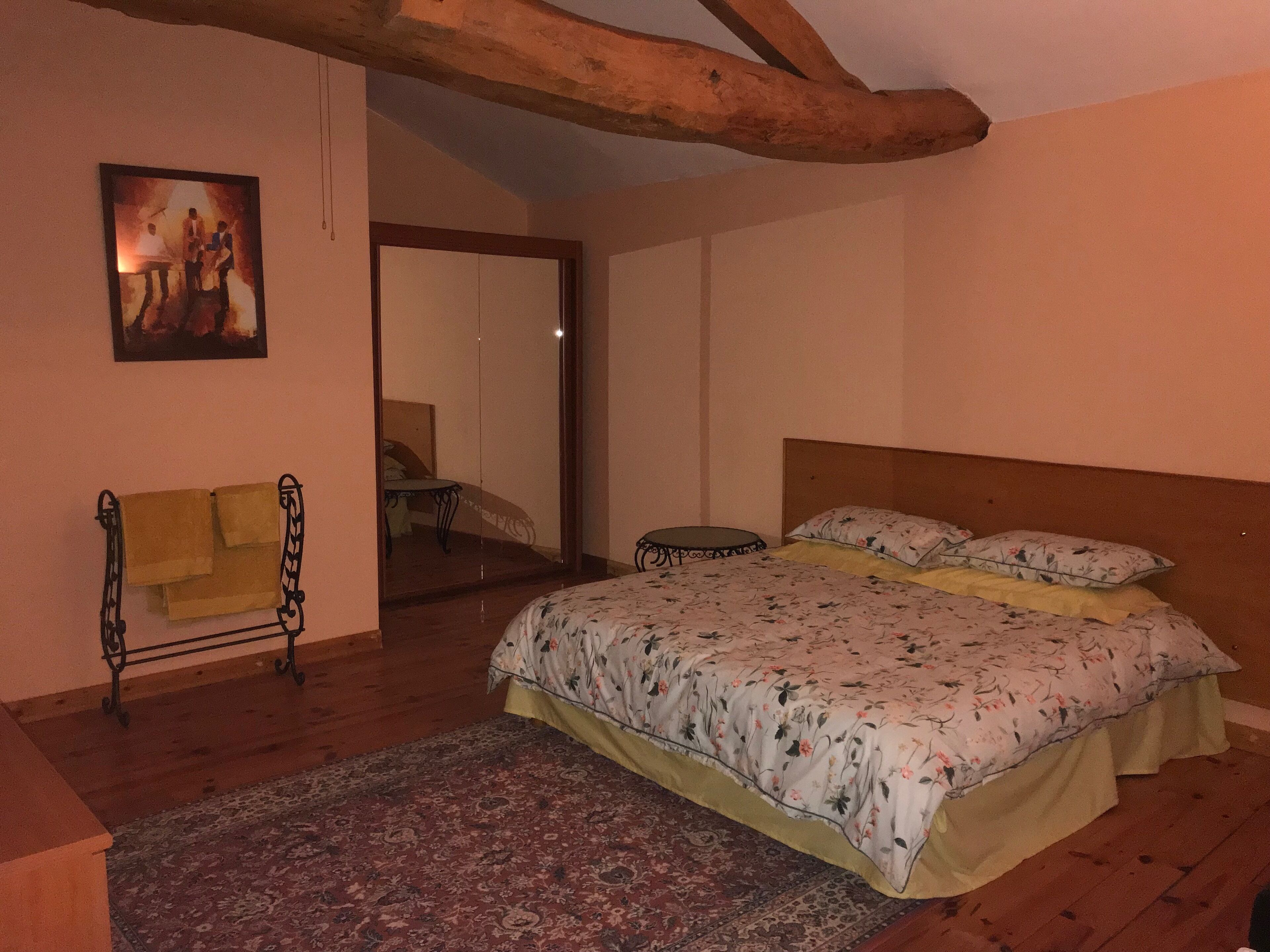 Une chambre à coucher avec un lit, une chaise, un miroir et un tableau accroché au mur.