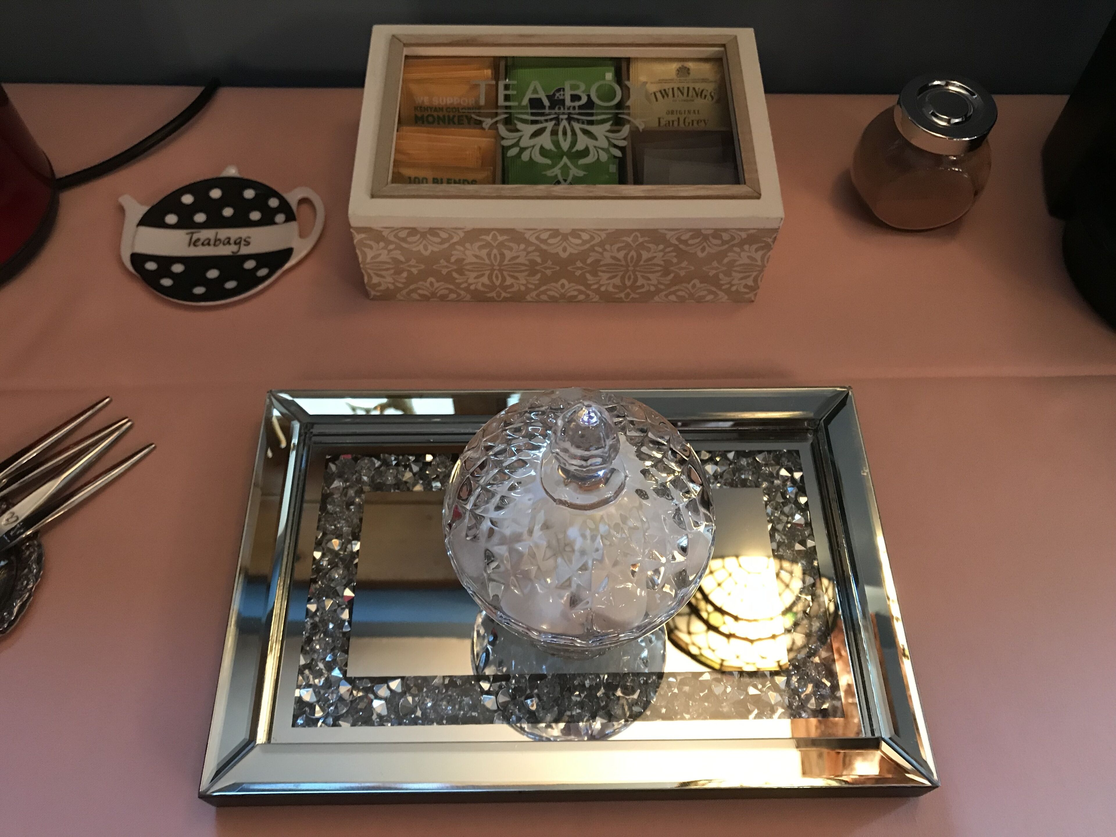 Un plateau avec un récipient en cristal et une boîte portant l’inscription « TEABO » est posé sur une table.