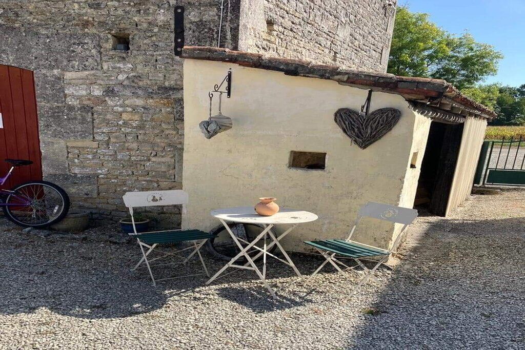 Ein rustikales Steinhaus mit einem kleinen Tisch, Stühlen, einem Fahrrad und einer herzförmigen Dekoration an der Wand.