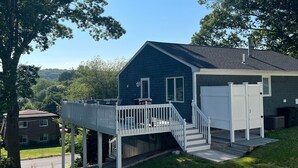 A two-story house with a covered deck and a garage. - Sunny Beach Getaway-Outdoor Shower, Big Deck, Walk to Coffee+Ice Cream-Sleeps 10 (Narragansett)