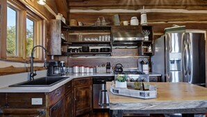 Eine rustikale Küche mit Holzschränken, einem Edelstahlkühlschrank und einer Marmorarbeitsplatte.