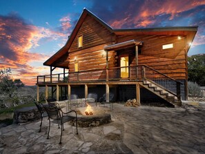 A log cabin with a stone patio, outdoor seating, and a fire pit. - Rustic meets Luxury with INCREDIBLE VIEWS! Hot Tub, Fire Pit, 2 bedrm/ 2 bath (San Marcos)