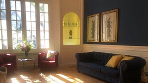 Una stanza con un divano blu, poltrone rosse, un tavolino con un vaso di fiori e una vetrina con una statua.