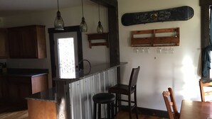 Una cocina con barra, armarios de madera y una estantería de vino montada en la pared.